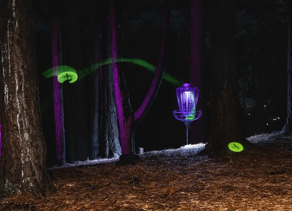 Glowing discs flying toward a lit basket at night