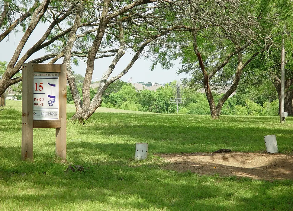 A hole 15 tee sign on a grassy, tree-lined course